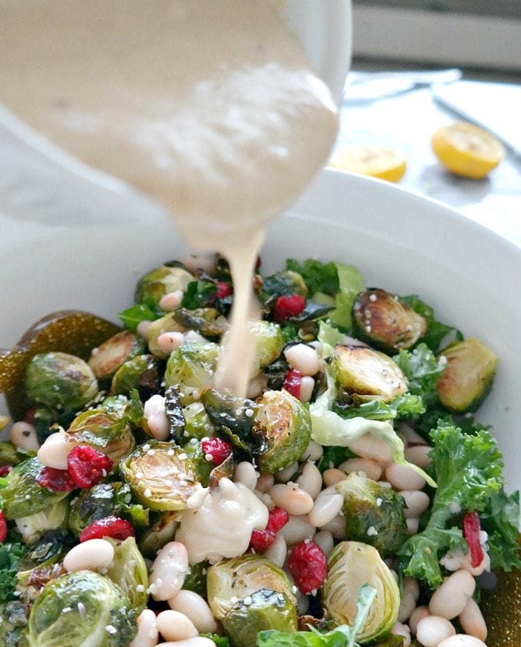 Holiday Kale & Cranberry Vegan Salad. A crowd-pleasing holiday favorite! Curly kale, crispy brussels sprouts, sweet cranberries and a delectably creamy tahini dressing with a lemony kick. From The Glowing Fridge